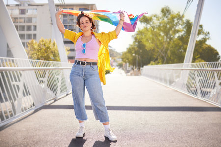 Rainbow, flag and lgbt woman portrait of a person with human rights, sexuality and equality support. Freedom, smile and gen z female on a urban city bridge with celebration of lgbtq with happinessの写真素材