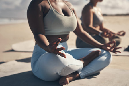 Yoga will allow you to find your Zen moment wherever, whenever. two young women meditating during their yoga routine on the beach.の写真素材