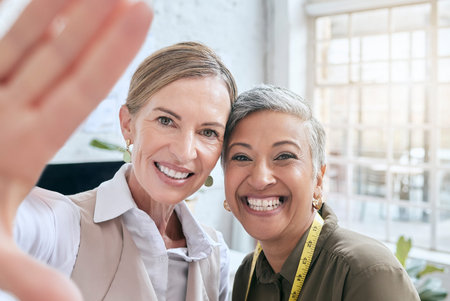 Fashion, designer and selfie of women in workshop taking pictures for happy memory. Face portrait, small business or senior female tailors taking photo for social media post while working in boutiqueの写真素材