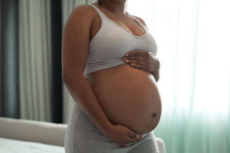 My tiny miracle. Closeup shot of an unrecognisable woman touching her pregnant belly at home.の写真素材