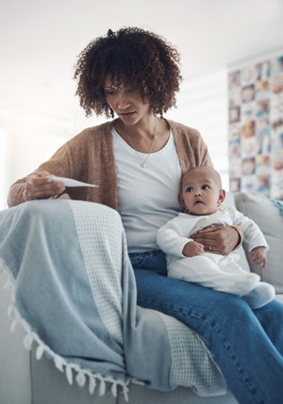 Is this a normal temperature for a baby. a young woman checking her babys temperature with a thermometer on the sofa at home.の写真素材