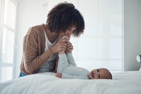 Every moment with your baby matters. a young woman playing with her adorable baby girl on the bed at home.の写真素材
