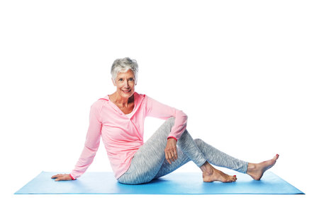 Yoga, portrait and senior woman in studio isolated on a white background. Zen chakra, pilates fitness and retired, elderly and happy female model sitting on mat and training for health and wellness.の写真素材