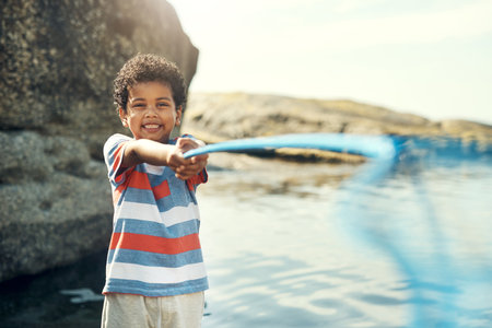 The ocean has amazing specimen. a young boy holding a fishing net at the beach.の写真素材