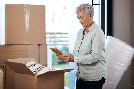 Packing up the past, preparing for the future. a senior woman looking at a photograph while packing boxes on moving day.の写真素材