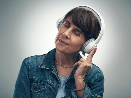 Music that puts you in the best reverie. Studio shot of a senior woman wearing headphones against a...