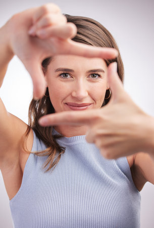 Hold that perfect pose for me. Studio portrait of a young woman making a finger frame against a grey background.の写真素材