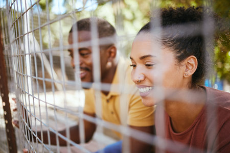 Happy couple, fence and smile at animal shelter, pet centre or zoo looking for a cute companion to...