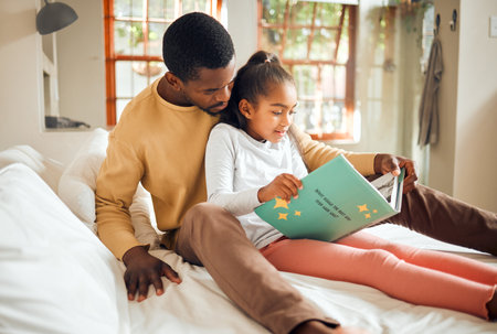 Black family, reading book and learning while on a bed for story time in house bedroom. Man or dad teaching girl child to read language, fantasy and development in happy home with love and supportの写真素材