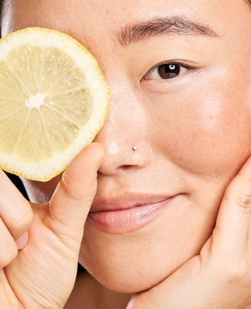 Skincare, beauty and portrait of an Asian woman with a lemon for body detox, health and wellness. Vitamin c, food and happy Japanese model with a fruit for diet, nutrition and vegan dermatologyの写真素材