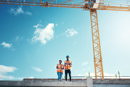 Staying on task keeps us on top. a young man and woman using a digital tablet on top of a building at a construction site.の写真素材