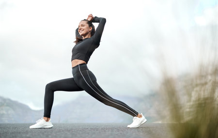 Taking in the fresh air while stretching. Full length shot of an attractive young woman stretching...