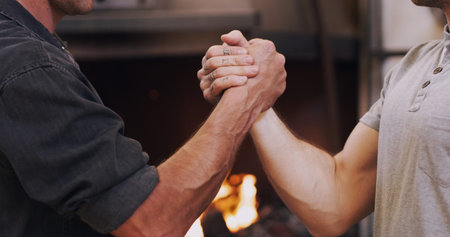 Together, were made of steel. two men shaking hands in a workshop.