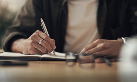 The hardest worker in the company hands down. an unrecognisable businessman writing in a notebook during a late night at work.の写真素材