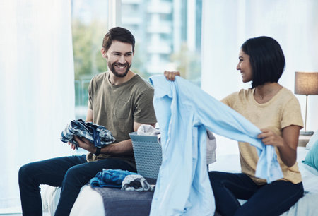 All is fair in love and laundry. a young couple doing laundry together at home.の写真素材