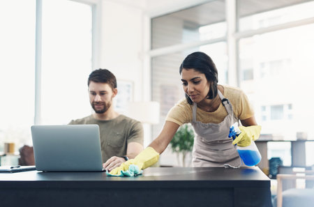 When life changes, learn how to work around it. a young woman cleaning the house while her husband...