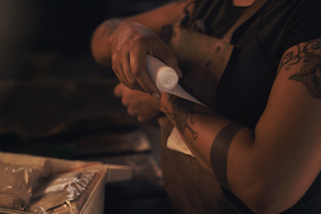 Make sure youre covered for workplace injuries. a woman wrapping a bandage around her wrist while working at a foundry.の写真素材