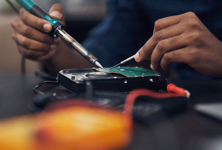 Getting down to the underlying issue. a technician using a soldering iron .to repair computer hardware.の写真素材