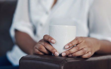 Chilling in the office lounge with some caffeine. Closeup shot of an unrecognisable businesswoman drinking coffee while taking a break in an office.の写真素材