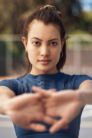 I absolutely refuse to lose. Portrait of a sporty young woman stretching her arms on a sports court.の写真素材