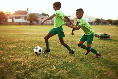 The game is starting to get intense. a group of young boys playing soccer on a sports field.の写真素材