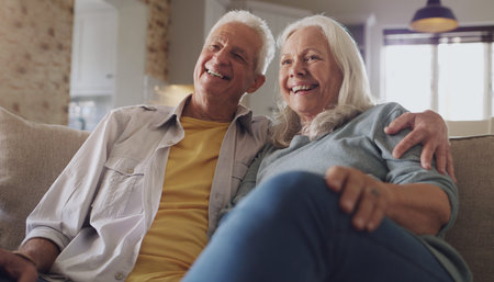 Retirement has turned us into happy couch potatoes. a happy senior couple sitting on the sofa at...