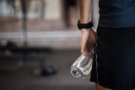 Water bottle, fitness and gym sports of a man at a wellness, training and exercise club with mockup. Sports, workout and athlete with mock up space ready for muscle and body development aloneの写真素材