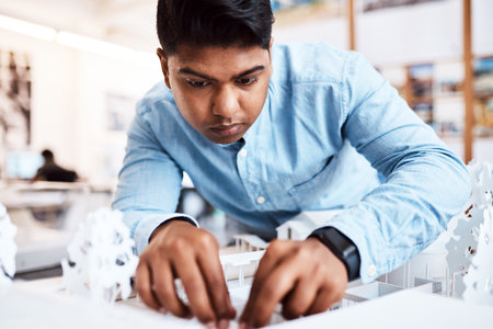 Embarking on his next building project. a young architect designing a building model in a modern office.の写真素材