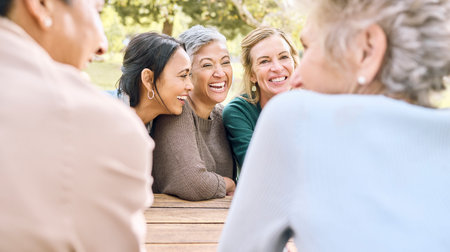 Senior, happy or friends in a park talking or speaking of funny gossip while relaxing holiday vacation in summer. Smile, old people or elderly women laughing at a crazy joke or bonding in natureの写真素材