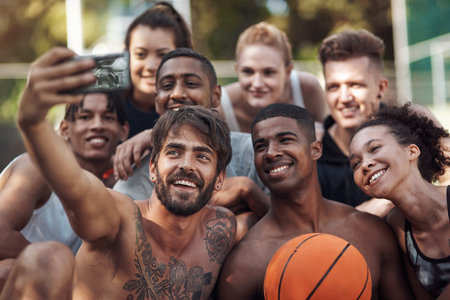 Just hanging on the court. a group of sporty young people taking selfies together on a sports court.の写真素材
