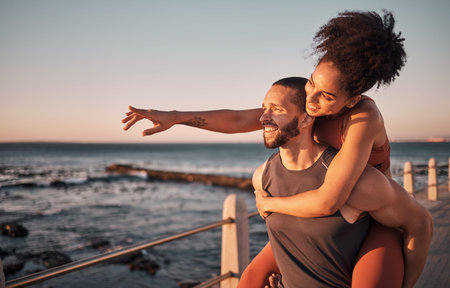 Fitness, couple and piggyback for beach sunset, travel or fun holiday journey together in the outdoors. Happy man and woman enjoying back ride by the ocean coast after running exercise or workoutの写真素材