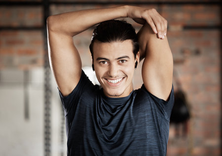Arm stretch, gym fitness and portrait of a man ready for exercise, training and wellness workout. Happy, smile and excited young person about to start sport health by stretching for sports aloneの写真素材