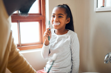 Daughter, father and brushing teeth in a bathroom for hygiene, grooming and bonding. Oral care, girl and parent for morning cleaning while having fun with black family who laugh and smile at homeの写真素材