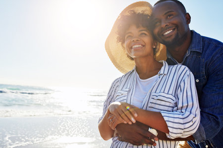 Beach hug, smile and black couple relax, travel and enjoy outdoor quality time together on Jamaica holiday mockup. Ocean sea water, blue sky flare and freedom peace mock up for happy bonding peopleの写真素材