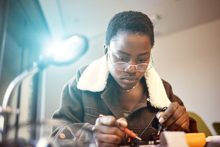 Black woman, student and engineer with electrical project while learning and studying. Education, engineering or technician at college with technology voltage meter for electricity and innovationの写真素材
