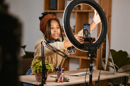 Communication, phone and influencer live streaming podcast, radio talk show or speaker talk about teen culture. Presenter microphone, black woman setup broadcast or speaking about online student newsの写真素材