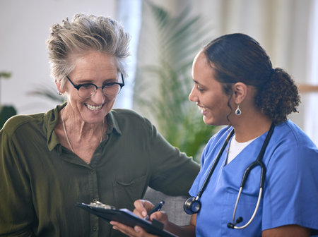 Healthcare, retirement and clipboard with a nurse and woman in consultation over treatment in a home. Medical, insurance and documents with a female medicine professional taking to a mature patientの写真素材