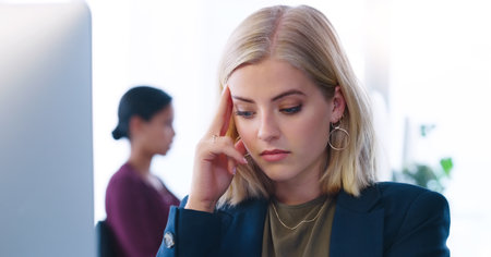 I have to keep my mind clear. a stressed young businesswoman seated at her desk while suffering from a headache in the office.の写真素材