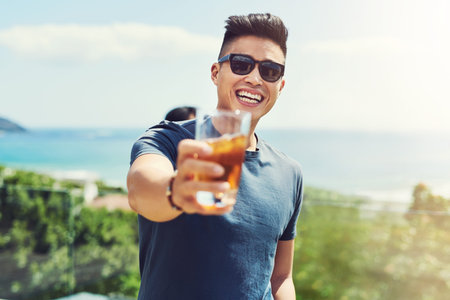 Come join us were here all summer long. Portrait of a handsome young man raising up his glass for a toast while relaxing outdoors with his friends.の写真素材