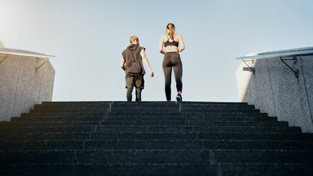 Taking the right steps to get to the top. Rearview shot of a young man and woman running up stairs together in the city.の写真素材
