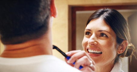Helping her man get a clean shave. a woman shaving her husbands facial hair in the bathroom at home.の写真素材