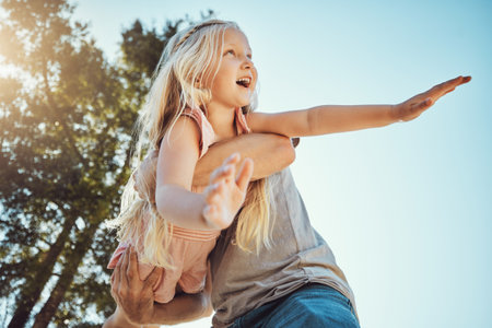 Child, father and playing in airplane game in nature park, home garden or house backyard in trust, support or summer break. Low angle, carrying and kid flying fun for happy girl, smile dad and parentの写真素材