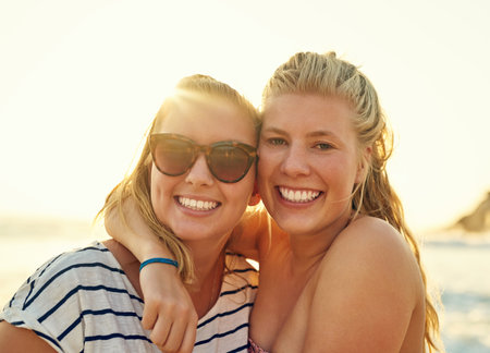 Never let your best friend go to the beach alone. young female best friends hanging out at the beach.の写真素材