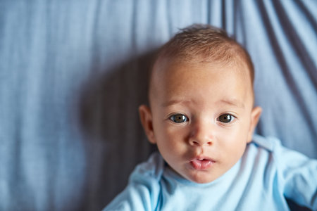 The sweetest face in the world. Portrait of an adorable baby boy laying on the bed at home.