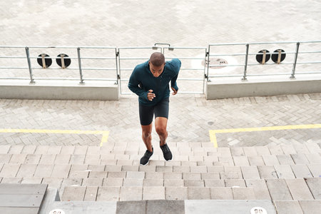 Working those quads. Full length shot of a handsome young athlete running up a flight of stairs...