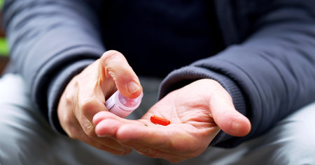 This should keep me stable for now. an unrecognizable elderly man about to take medication outside in a park during the day.の写真素材