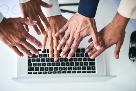Reach more people through the world online. Closeup shot of an unrecognizable group of businesspeople reaching towards a laptop in an office.の写真素材
