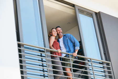 Love puts you on top of the world. a happy couple standing on the balcony of their home.の写真素材