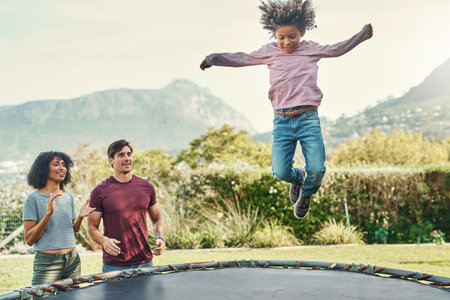 Hes our little high flyer. an adorable little boy jumping on a trampoline with his parents watching...
