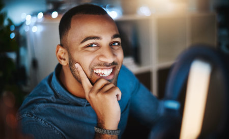 Working late is a breeze. Portrait of a young businessman using a computer during a late night at work in a modern office.の写真素材